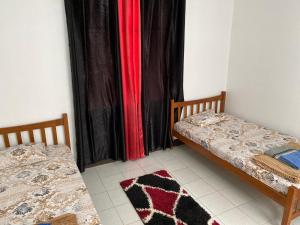 two beds in a room with black and red curtains at Chez Bibi in Maison Blanche