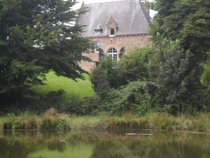 um edifício de tijolos com uma janela do lado de um lago em Gite de Peche em Saint-Ellier-du-Maine