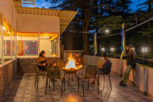 a group of people sitting around a fire pit on a patio at The Hosteller Mcleodganj, Mall Road in McLeod Ganj
