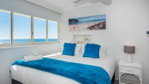 1 dormitorio con 1 cama grande con almohadas azules en Viscount on the Beach en Gold Coast