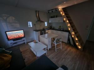 een woonkamer met een keuken, een televisie en een trap bij Huisje in Pieterburen in Pieterburen