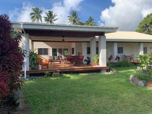 a house with a large wooden deck in the yard at Rutaki Retreat in Rarotonga