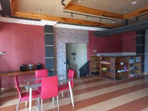 a dining room with pink chairs and a brick wall at Collection O 92242 Hotel Tanjung Emas in Purwokerto