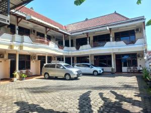 two cars parked in a parking lot in front of a building at Collection O 92242 Hotel Tanjung Emas in Purwokerto