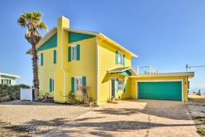 una casa amarilla con garaje y palmera en Flagler Beach Oceanfront Haven with Hot Tub!, en Flagler Beach
