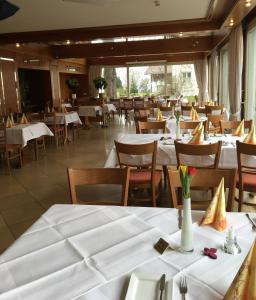 ein Restaurant mit Tischen und Stühlen mit weißem Tischtuch in der Unterkunft Hotel Engel in Ulm