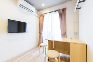 a room with a desk and a tv on a wall at JP INN Kyoto Ekimae Izutsucho in Kyoto