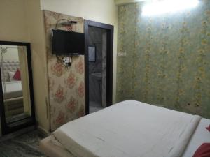ein Schlafzimmer mit einem Bett und einem TV an der Wand in der Unterkunft Hotel Shiv Mahima Inn By WB Inn in Allahabad