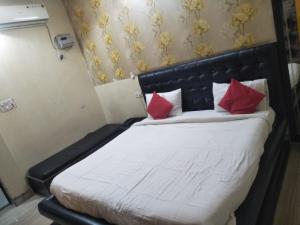 Bett mit roten Kissen auf einem Zimmer in der Unterkunft Hotel Shiv Mahima Inn By WB Inn in Allahabad