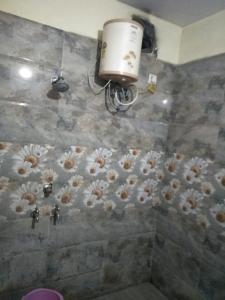 ein Bad mit einer Dusche mit Blumen an der Wand in der Unterkunft Hotel Shiv Mahima Inn By WB Inn in Allahabad