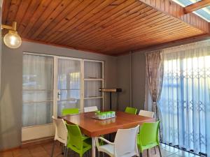 a dining room with a wooden table and green chairs at Step-by-Step Self-Catering and B&B in Bellville