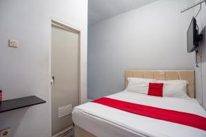 um quarto com uma cama com um cobertor vermelho em RedDoorz near Margonda Raya em Kemirimuka Dua