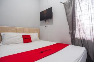 a bedroom with a red blanket on a bed at RedDoorz near Margonda Raya in Kemirimuka Dua