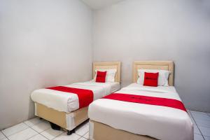 two beds sitting next to each other in a room at RedDoorz near Margonda Raya in Kemirimuka Dua