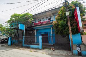 Um edifício azul com um cão à frente. em RedDoorz near Margonda Raya em Kemirimuka Dua