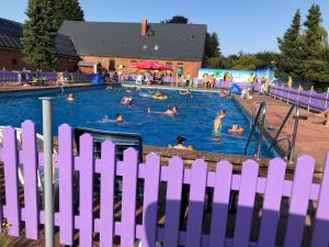 ein lila Zaun vor einem Pool mit Menschen darin in der Unterkunft Märchencamping in Stuhr
