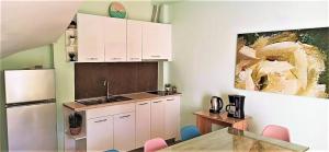 a kitchen with white cabinets and a table and a refrigerator at Grace : Garden and Terrace House in Kavala
