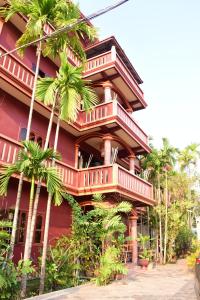 a red building with palm trees in front of it at Bou Savy Guesthouse in Siem Reap