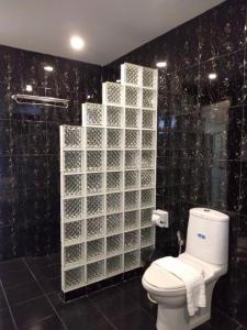 baño con aseo y pared de azulejos negros en Private Pattaya Resort en Nong Prue