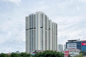 een hoog wit gebouw in een stad bij RedLiving Apartemen Puri Orchard - Prop2GO Home Tower Magnolia in Jakarta
