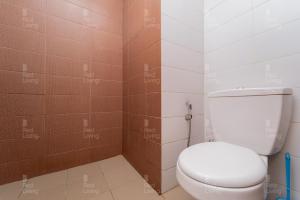 een badkamer met een wit toilet en bruine tegels bij RedLiving Apartemen Puri Orchard - Prop2GO Home Tower Magnolia in Jakarta