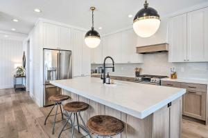a kitchen with white cabinets and a large island with stools at Mountain-View Townhome Near Powder Mountain! in Huntsville