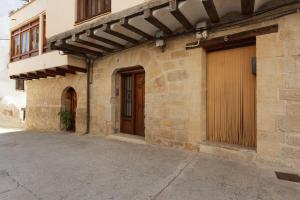 a stone building with a door and a garage at Apartamentos La Pastora in Peñarroya de Tastavins