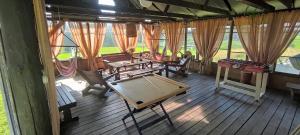 ein Zimmer mit Tischen und Stühlen auf einer Holzterrasse in der Unterkunft Vēsturiska viensēta Kārkliņi in Cēsis