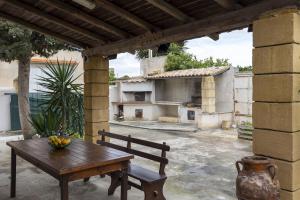 a wooden table and a bench on a patio at Villetta Il Gallo in Mazara del Vallo
