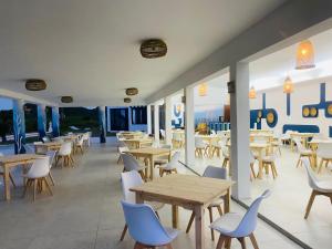 un restaurante con mesas y sillas de madera y ventanas en Ponta Mar Resort en Ponta do Ouro