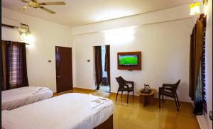 a hotel room with two beds and a tv at Rosan Heritage - A Beach Villa in Kanyakumari