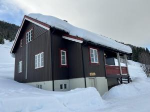 ein Haus mit Schnee auf dem Dach im Schnee in der Unterkunft Svarteberg Drengestugu - cabin by Ål skisenter in Ål
