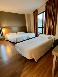 ein Hotelzimmer mit 2 Betten und einem Fenster in der Unterkunft Hotel Duero in Laguna de Duero