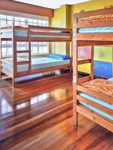 a room with three bunk beds and a wooden floor at Meiga Backpackers Hostel in Santiago de Compostela