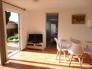 un soggiorno con TV, tavolo e sedie di Bas de villa jardin plein sud proche mer clim-Wifi a Saint-Mandrier-sur-Mer