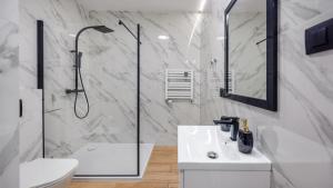 a white bathroom with a shower and a sink at Apartamenty Sun & Snow Baltic Nova in Władysławowo