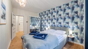 a bedroom with a bed with blue pillows on it at Apartamenty Sun & Snow Baltic Nova in Władysławowo