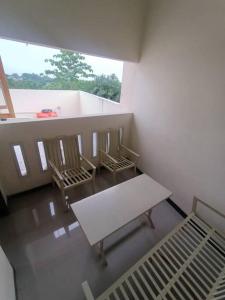 Zimmer mit 3 Stühlen, einer Bank und einem Fenster in der Unterkunft Anugrah homestay in Cirebon