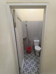 a bathroom with a toilet and a red bucket at Anugrah homestay in Cirebon