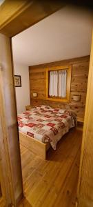 een slaapkamer met een bed en een houten vloer bij Chalet La Stua in Cavalese