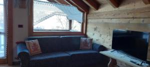 a living room with a blue couch and a fireplace at Chalet La Stua in Cavalese