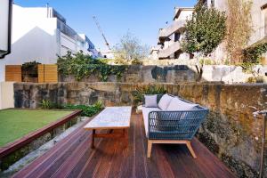 einen Stuhl und einen Tisch auf einer Holzterrasse in der Unterkunft Crooked Floor House - 1st floor in Porto