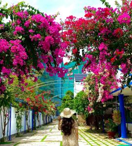 una mujer caminando por una calle con flores rosas en La Vita Hotel en Vung Tau