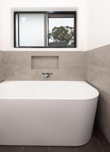 a white bath tub in a bathroom with a window at Batemans Bay Delight - Pet Friendly in Batemans Bay