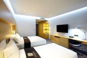 um quarto de hotel com duas camas e uma televisão em Eldis Regent Hotel em Daegu