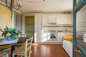 una cocina con armarios blancos y una mesa con un jarrón de flores en Limoni, en Molazzana