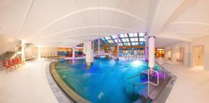 a large swimming pool in a building with a ceiling at The Little Pool House in Wagrain