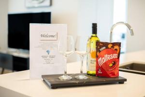 a bottle of wine and two wine glasses on a counter at Stylish Stay for Couples in CBD by Stylish Stays in Brisbane