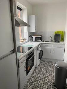 uma cozinha com armários brancos e um forno com placa de fogão em Quirky one bed flat, Barbican area, Plymouth em Plymouth