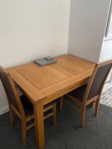 a wooden table with two chairs and a book on it at Quirky one bed flat, Barbican area, Plymouth in Plymouth